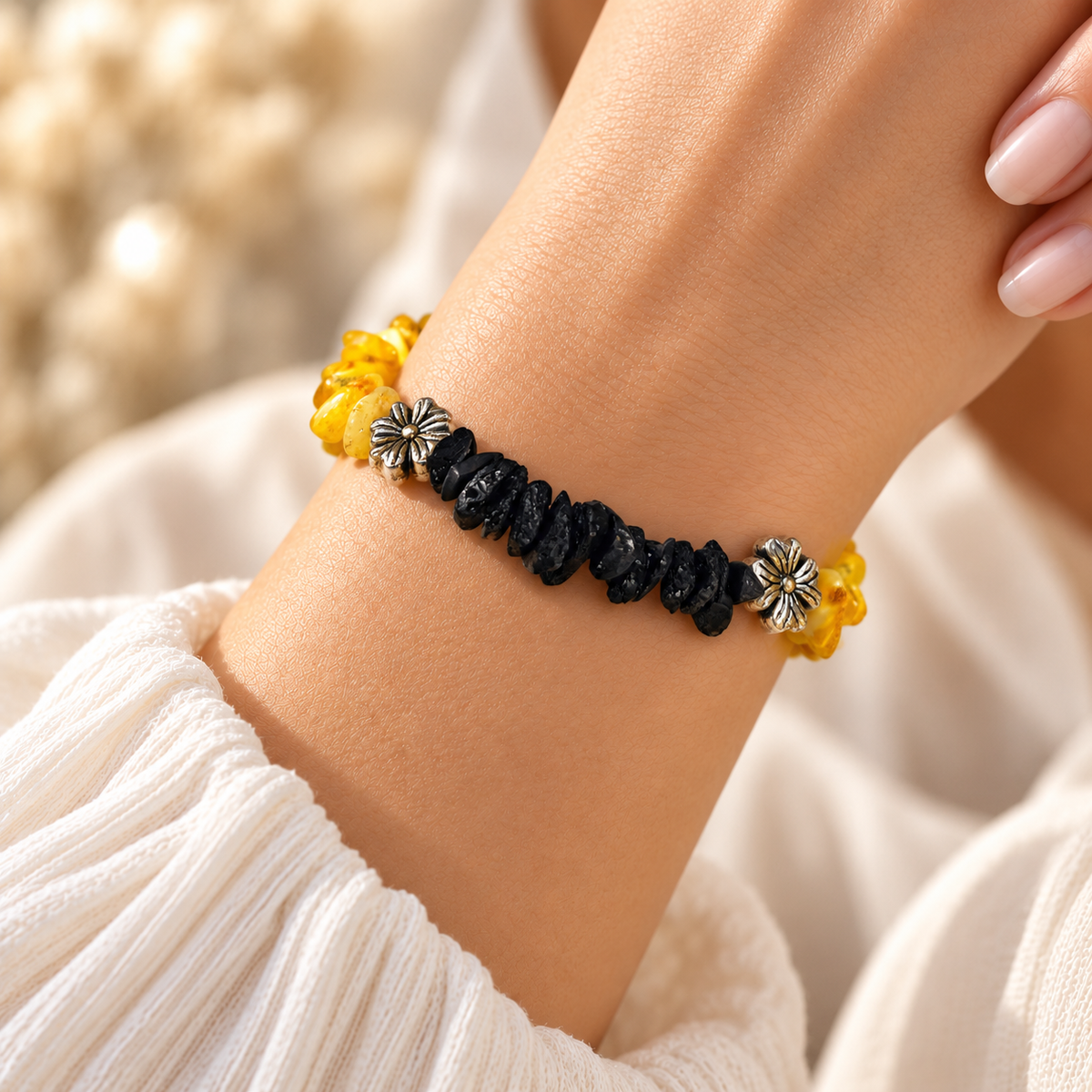 KIZIMA yellow and black amber bracelet worn on a woman's wrist, showing its contrasting chips and flower spacers.