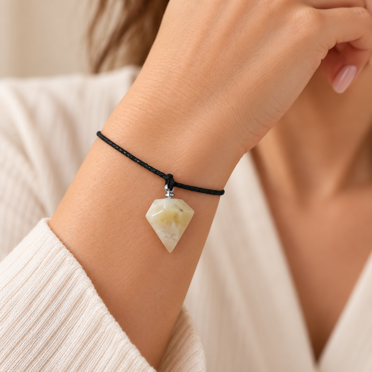 KIZIMA 3G0125q0.80 cream amber pointed pendant bracelet on black cord worn on an adult woman’s wrist