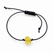 Faceted transparent amber bead on an adjustable black cord bracelet against a white background