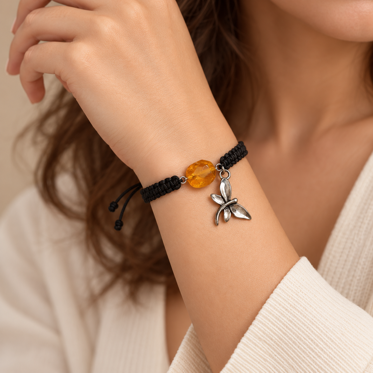 KIZIMA 3G0125q2.76-1 honey amber black macrame bracelet with silver-tone dragonfly charm worn on an adult woman's wrist