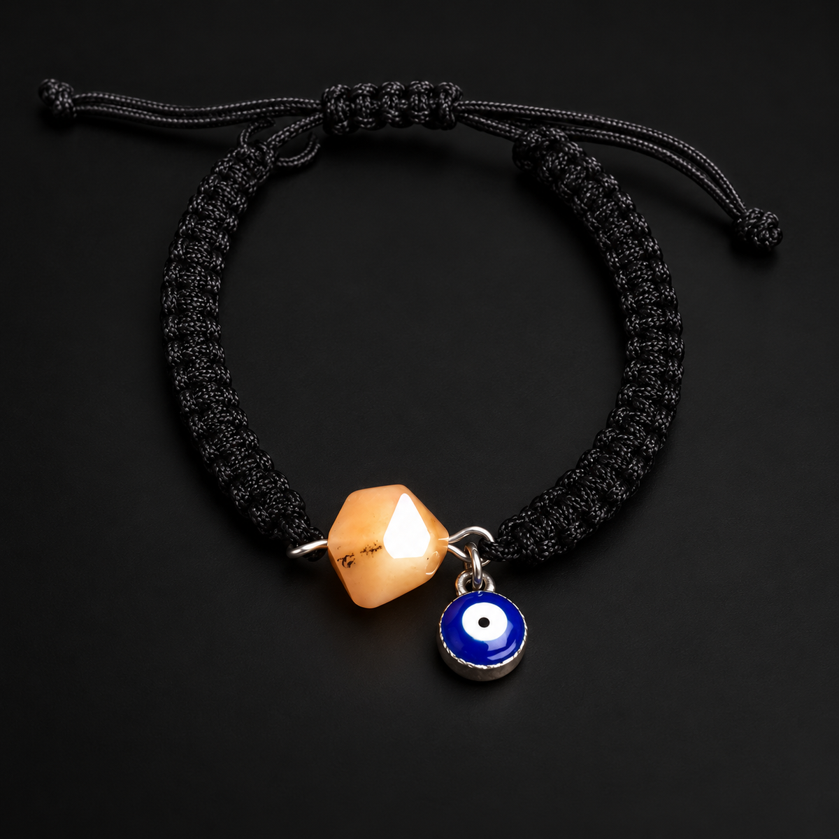 KIZIMA 3G0125q2.76-2 pale peach amber black macrame bracelet with blue evil-eye charm on a black studio background