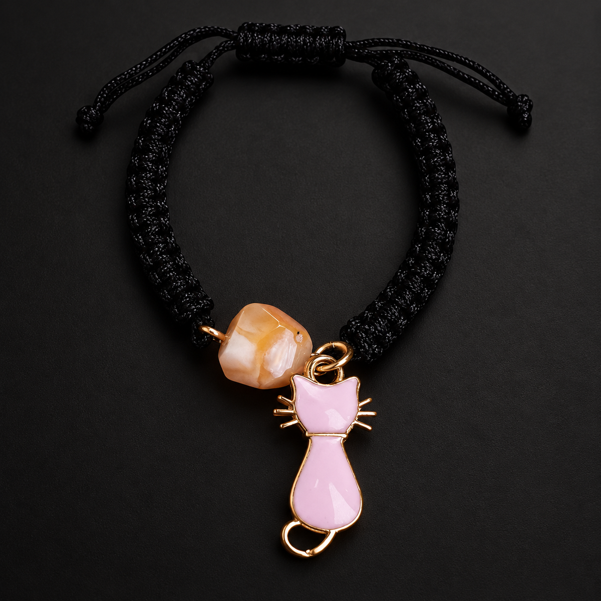 KIZIMA 3G0125q2.76-3 pale peach amber black macrame bracelet with pink cat charm on a black studio background