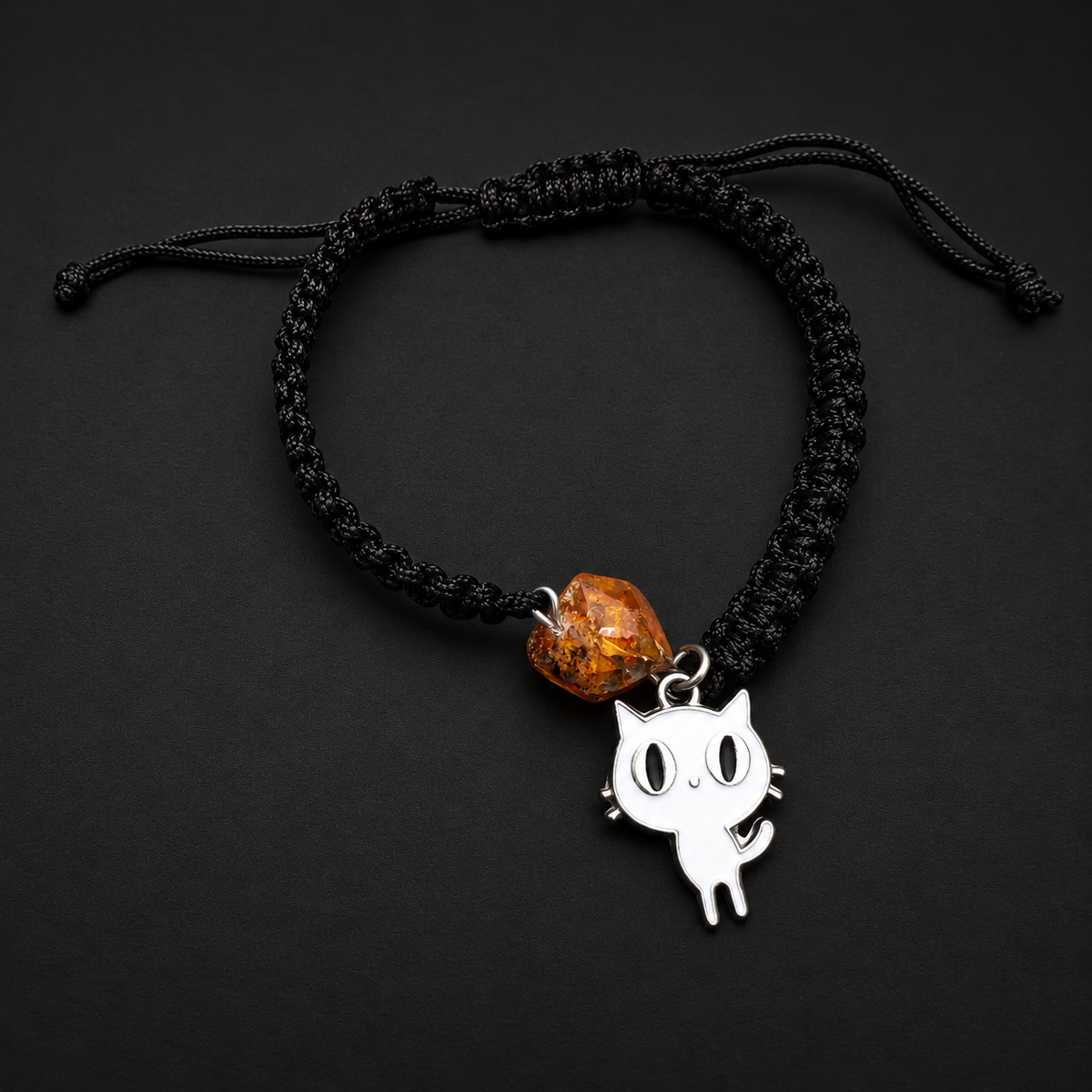 KIZIMA amber bracelet with a white cat charm and adjustable black macrame band in a black studio