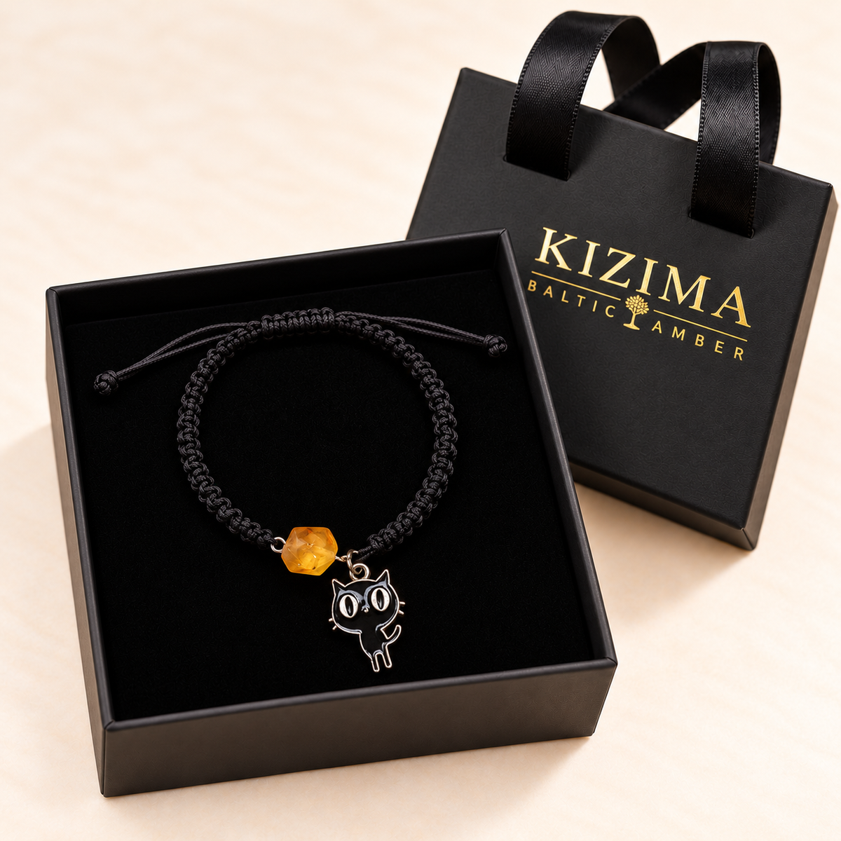 Black cat charm and honey amber bracelet resting on clean black velvet inside a KIZIMA gift box
