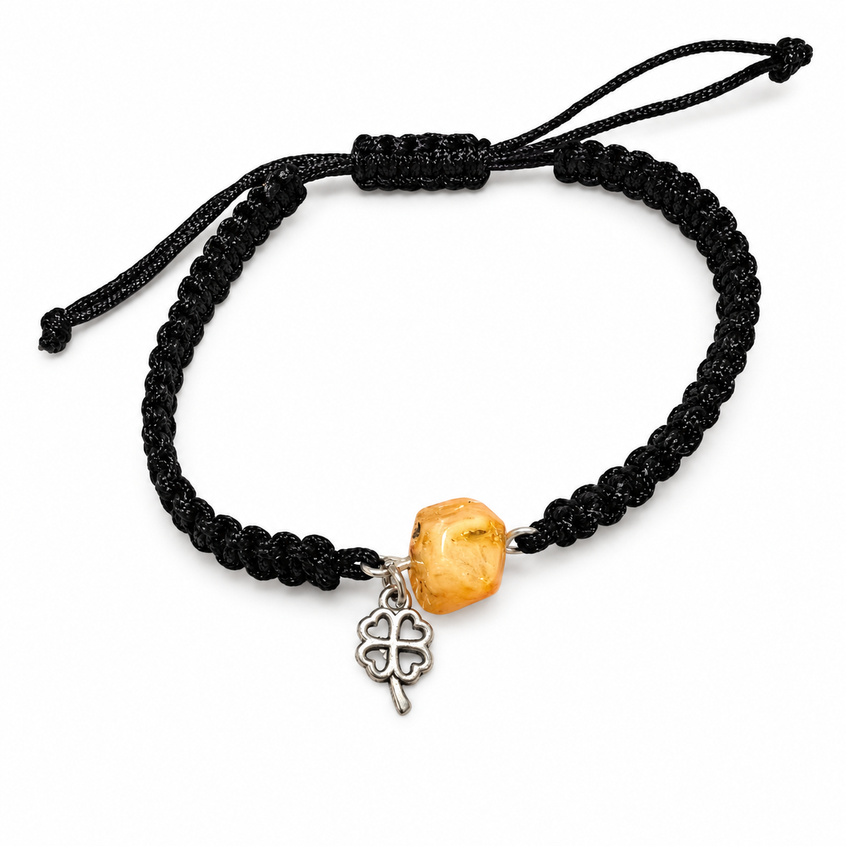 Adjustable black macrame bracelet with a honey amber pebble and open silver-tone clover charm on white