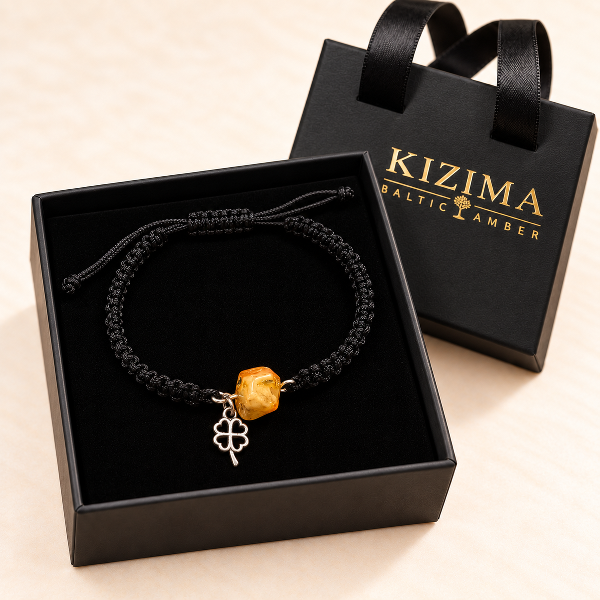 Amber and open clover charm bracelet arranged on pristine black velvet in a KIZIMA gift box