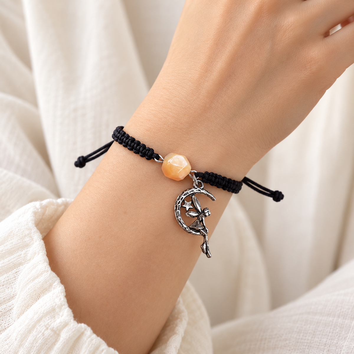 KIZIMA single creamy amber bead and silver-tone moon fairy bracelet on a young adult woman's wrist