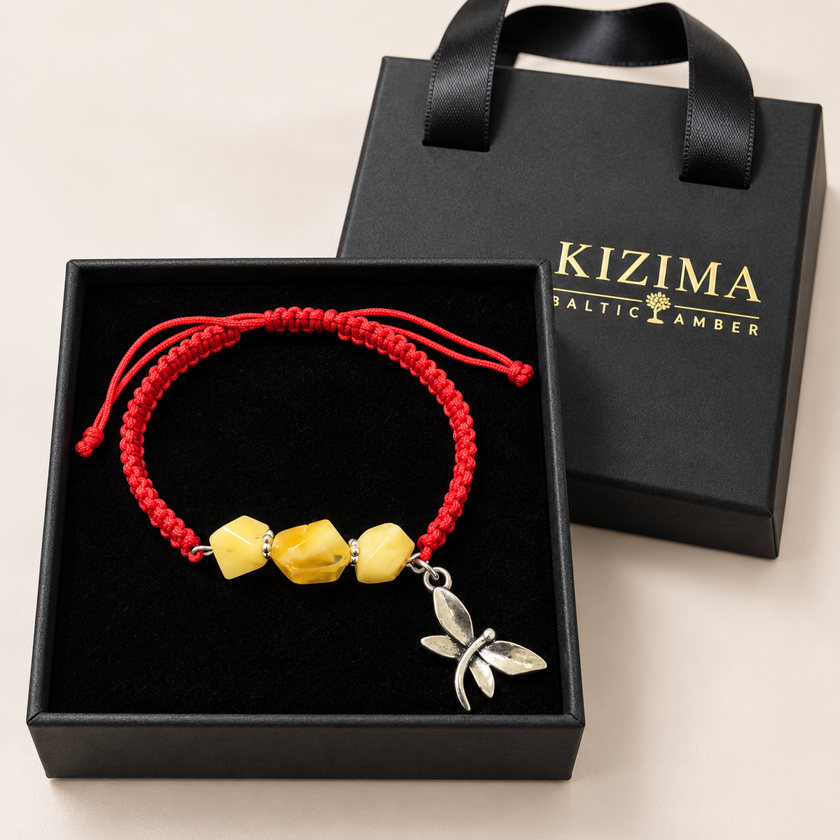 KIZIMA three yellow amber stones and silver-tone dragonfly charm on red macrame bracelet inside a black KIZIMA gift box