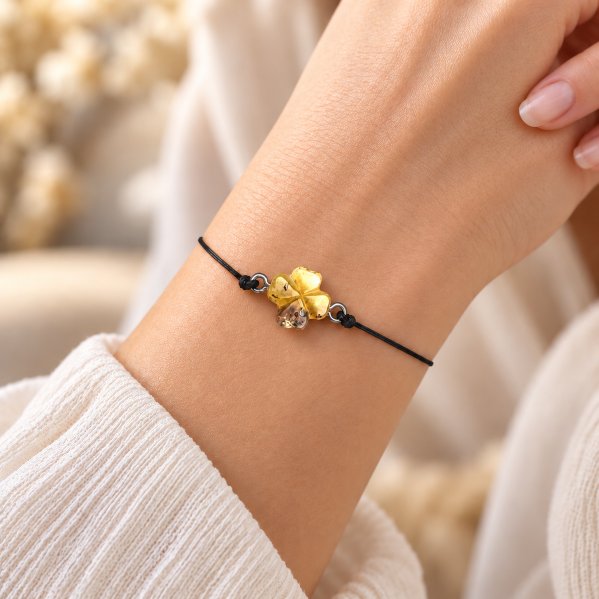 Four-leaf amber clover bracelet on a woman's wrist with its delicate black cord