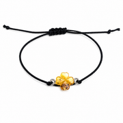 Yellow amber clover charm and black sliding-knot bracelet on a pure white background