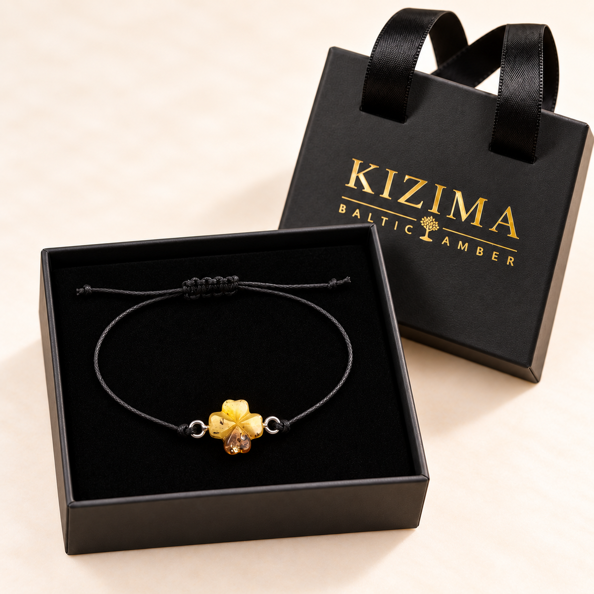 KIZIMA amber clover cord bracelet displayed on clean black velvet in the branded gift box