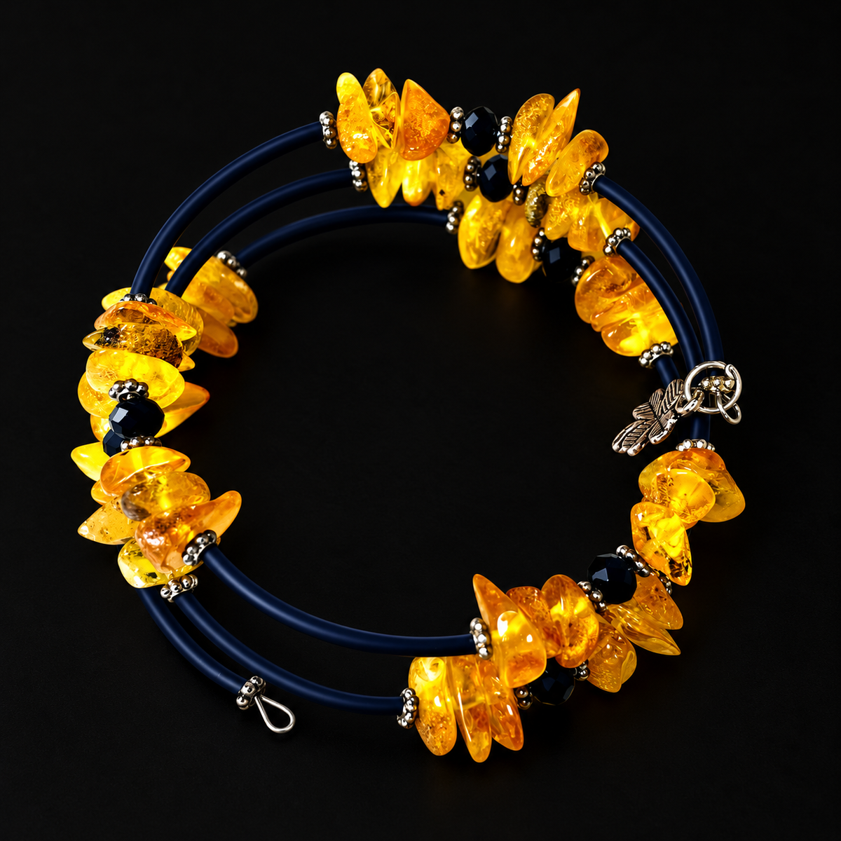KIZIMA 3G250q16 three-coil spiral bracelet with yellow amber, dark navy sections and black faceted beads on a black studio surface