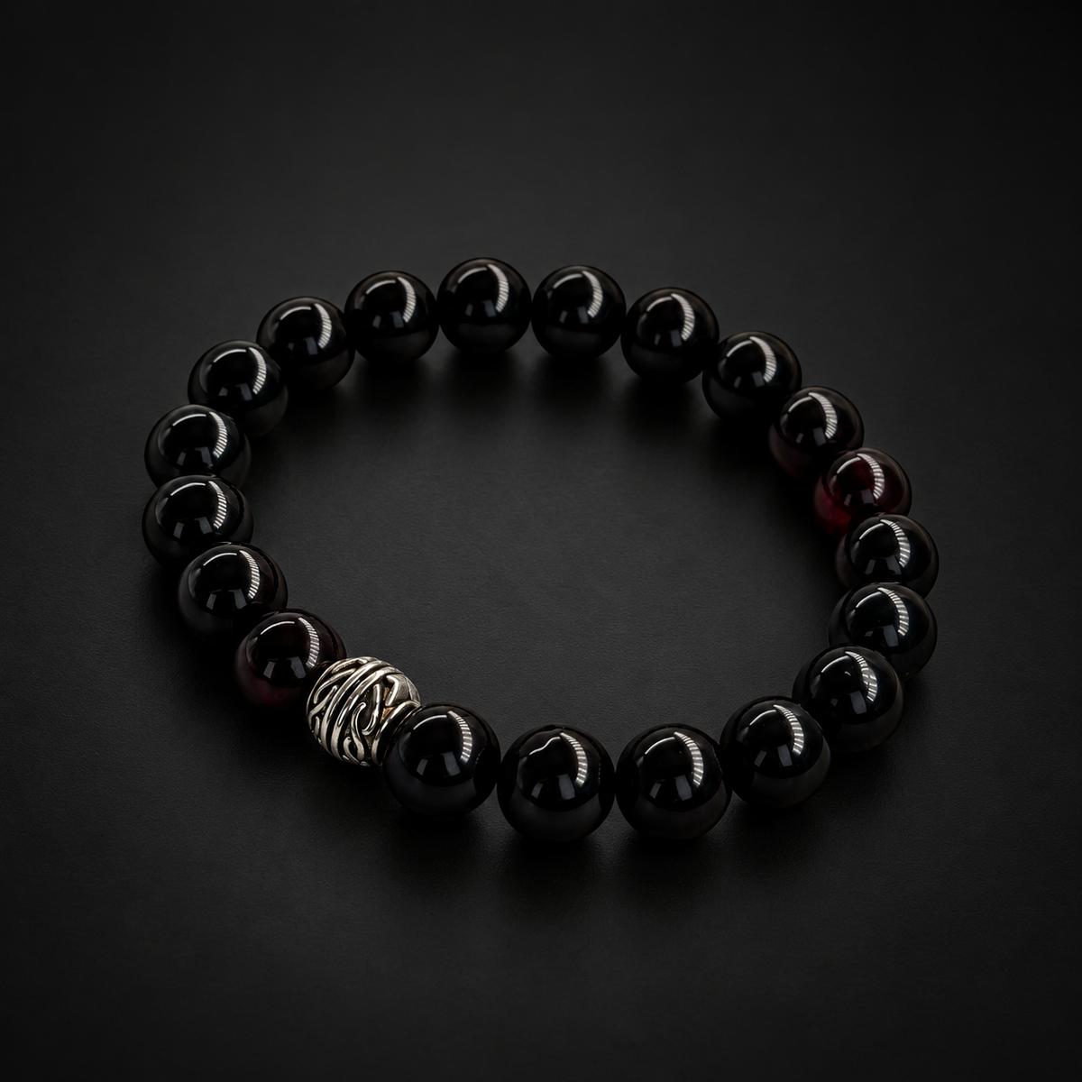 Glossy black amber bead bracelet by KIZIMA with a single silver-tone patterned bead under black studio lighting.