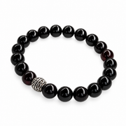 KIZIMA black amber stretch bracelet with round beads and a patterned metal accent isolated on pure white.