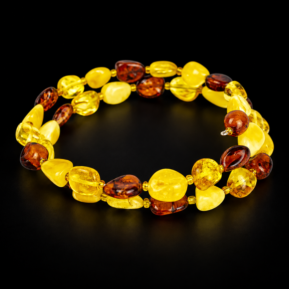 KIZIMA two-turn yellow and cognac amber pebble spiral bracelet in a black studio