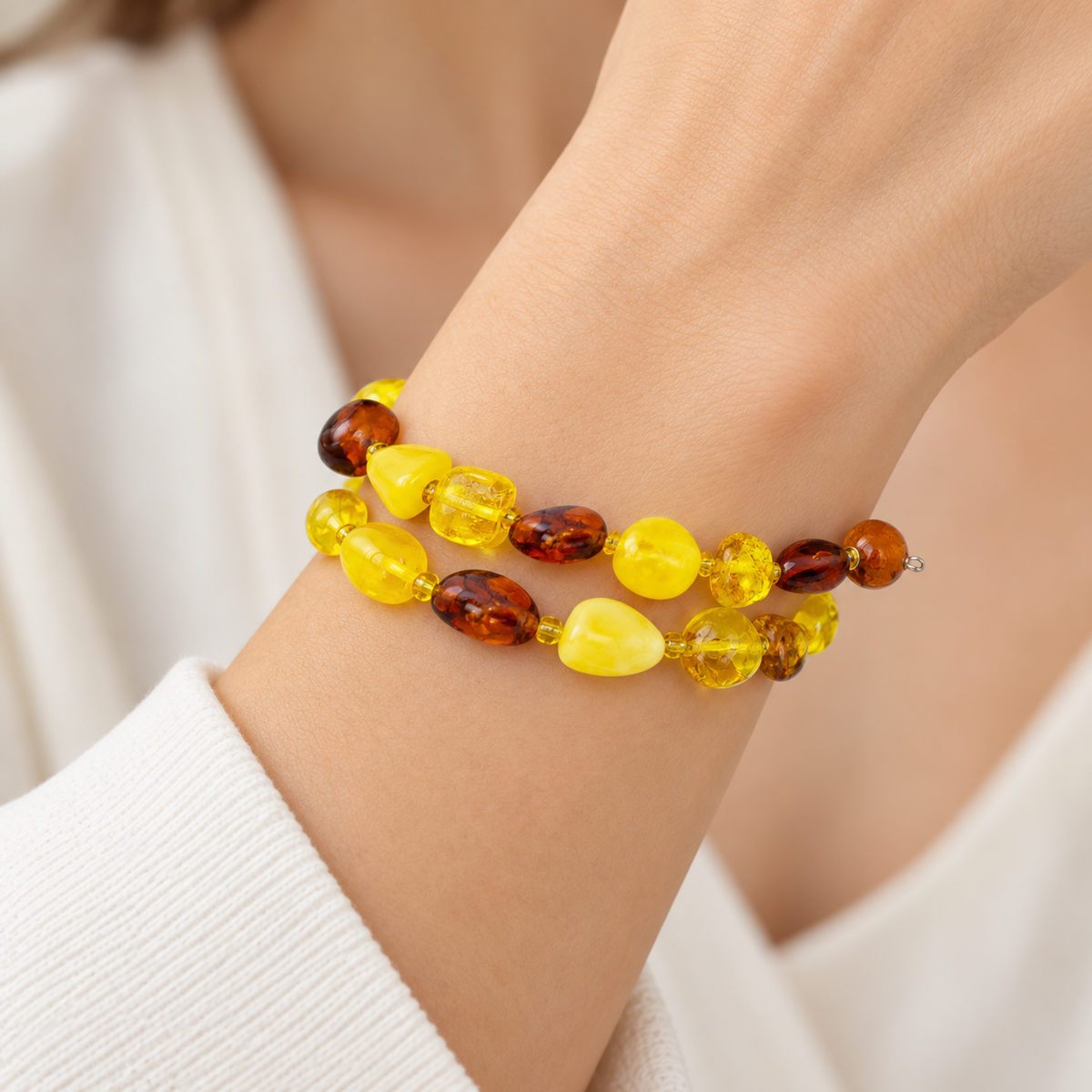 KIZIMA two-turn yellow and cognac amber pebble spiral bracelet on a young adult woman's wrist