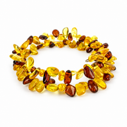 Natural yellow and cognac amber chip spiral bracelet, with its looped wire ends, on white.