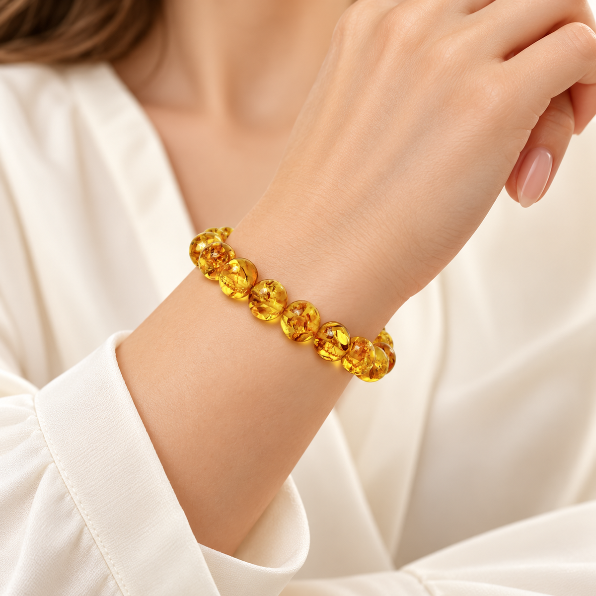 Honey-yellow amber bead stretch bracelet with cognac inclusions on a young adult woman's wrist.