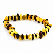 Irregular buttery yellow and dark cherry amber chips arranged in a stretch bracelet on white.
