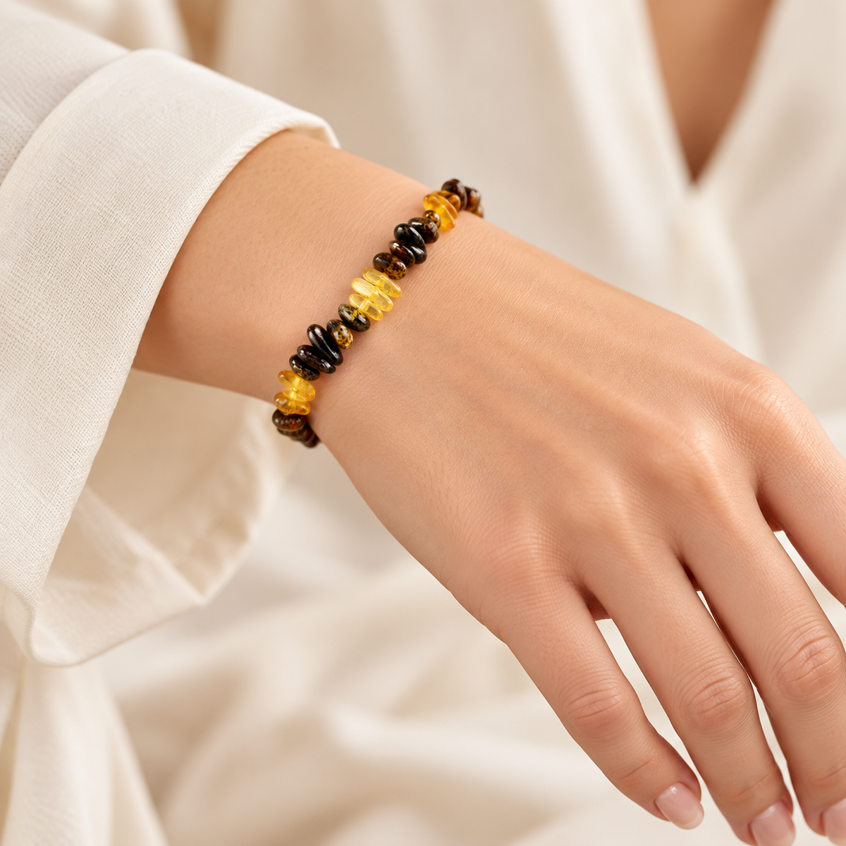 KIZIMA yellow and dark mottled amber nugget bracelet on a young adult woman's wrist.