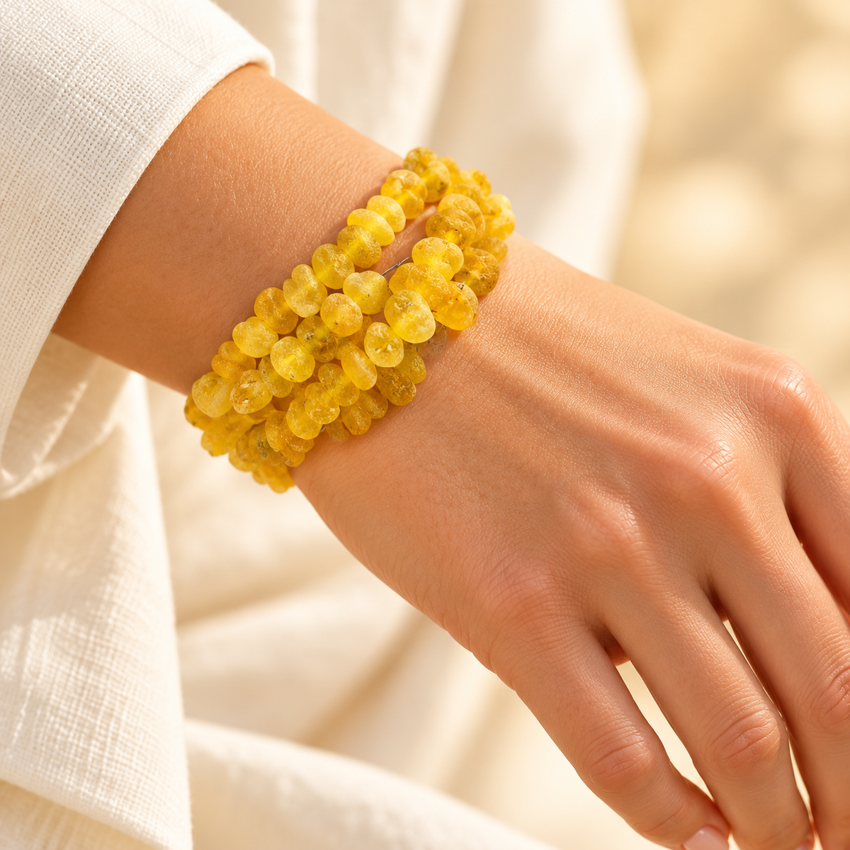 KIZIMA frosted yellow amber three-coil wrap bracelet worn on a young adult woman's wrist.