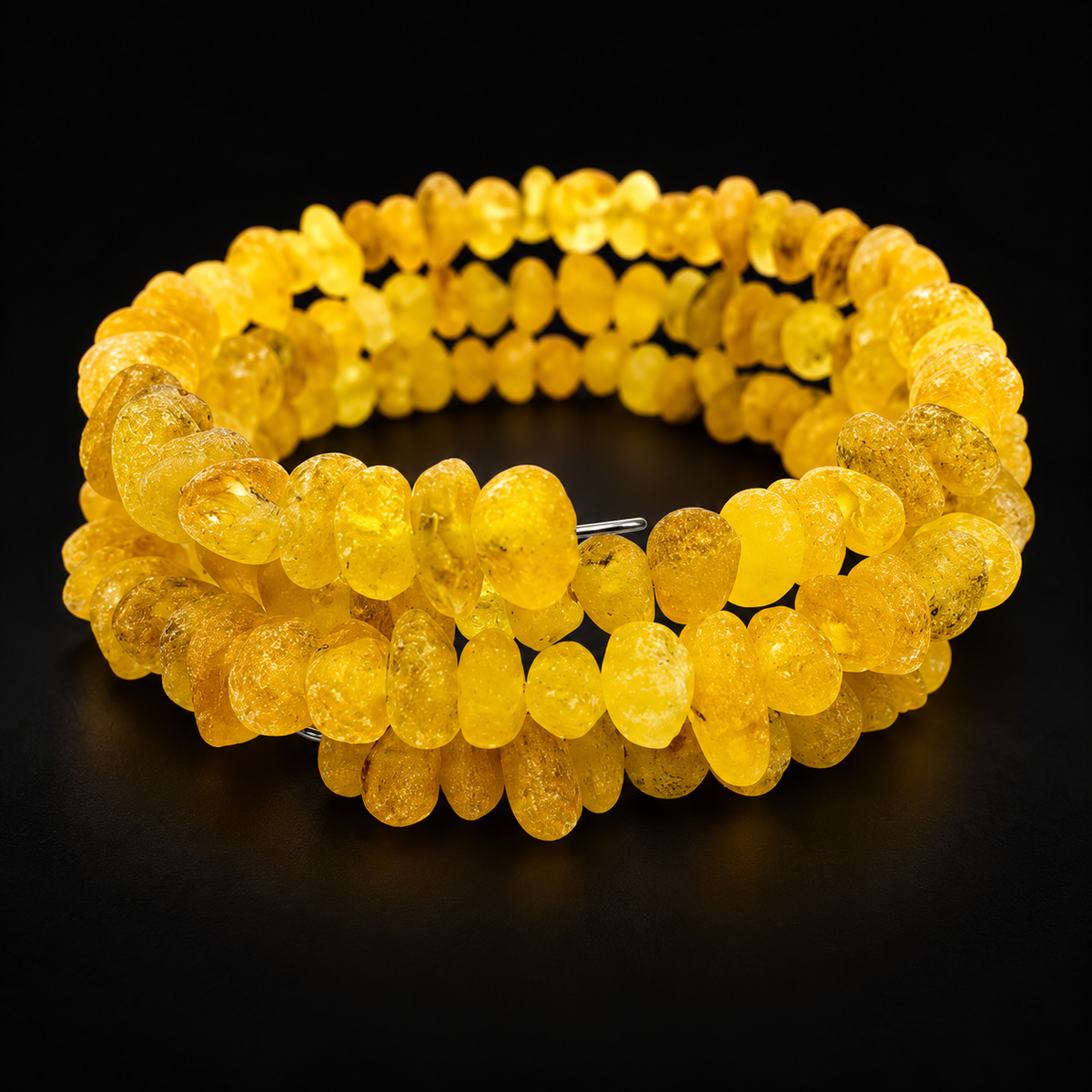 KIZIMA frosted yellow amber three-coil wrap bracelet on a black studio background.