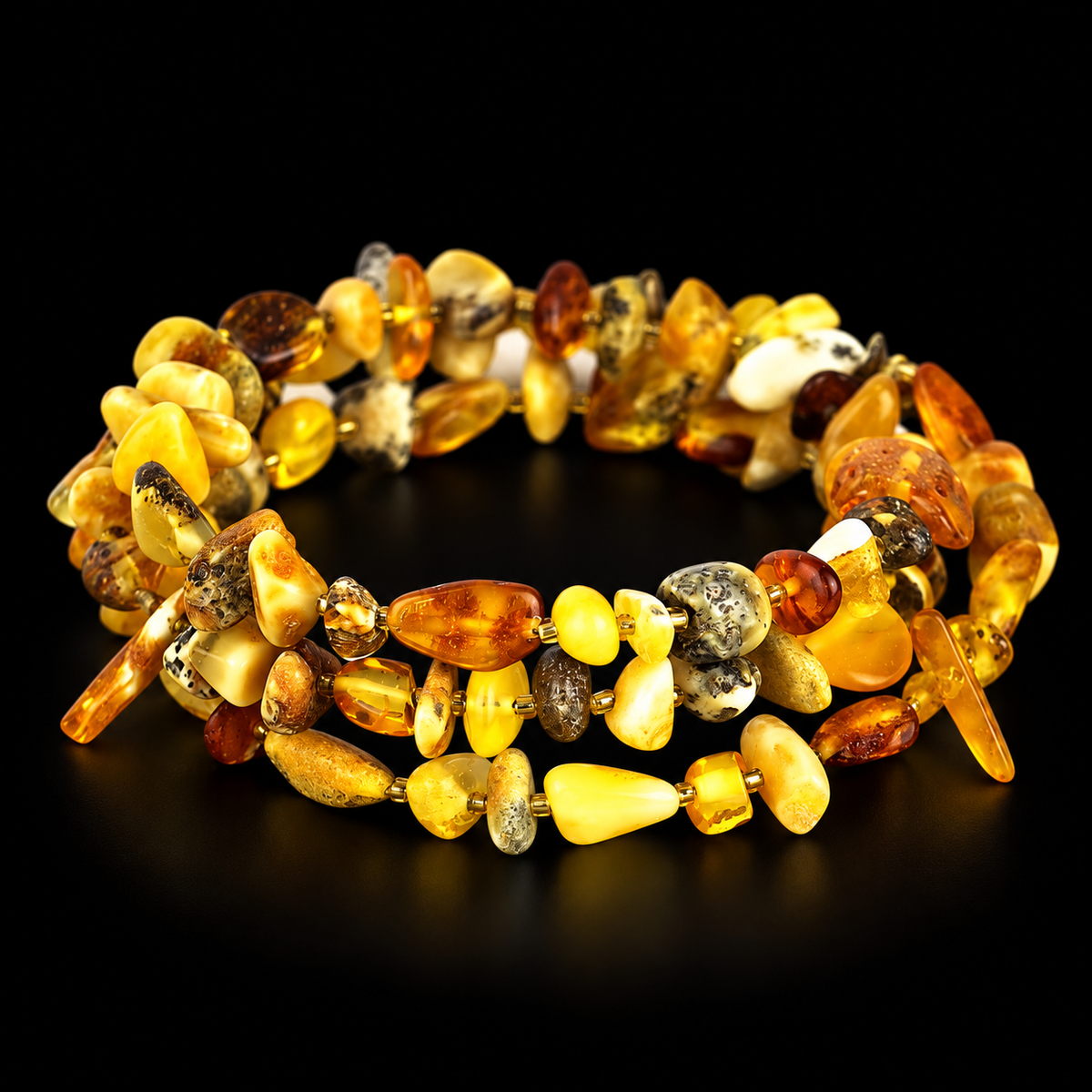 KIZIMA multicolor Baltic amber chip spiral bracelet with tiny gold-tone spacers in black studio light.