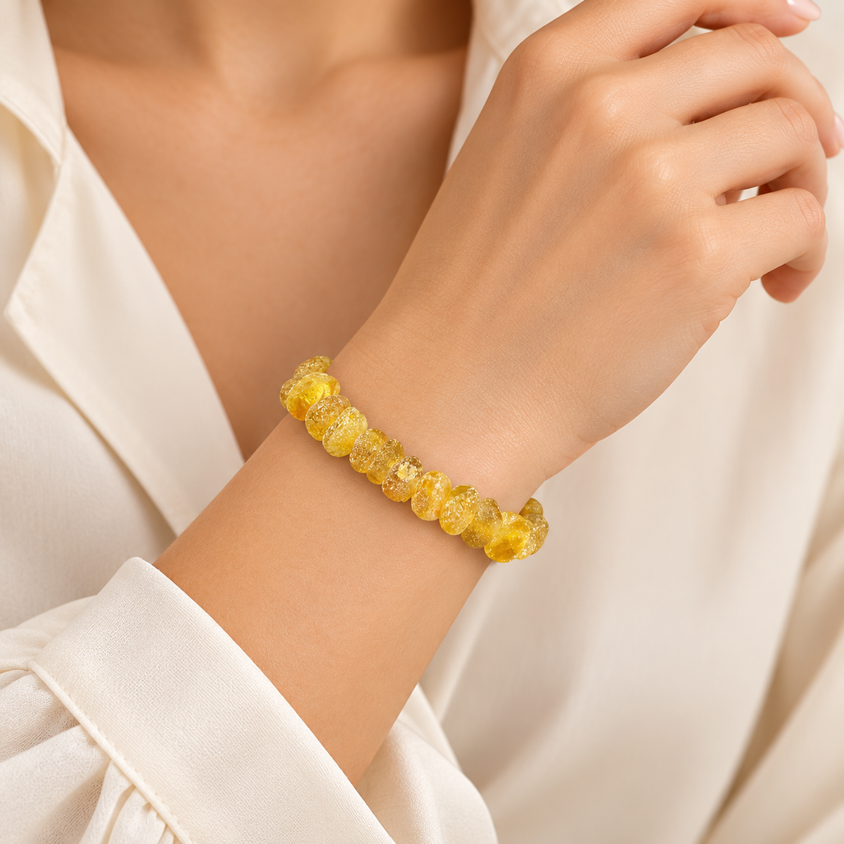 Small frosted yellow amber nuggets in a bracelet on a young adult woman's wrist.