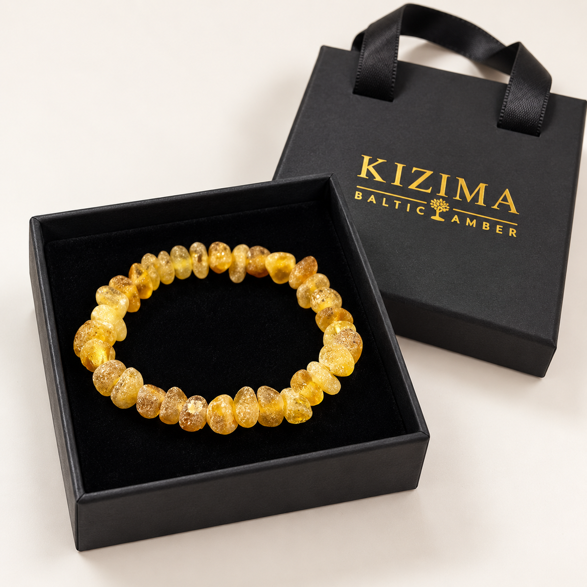 Raw honey-yellow amber bracelet on spotless black velvet in a KIZIMA gift box.