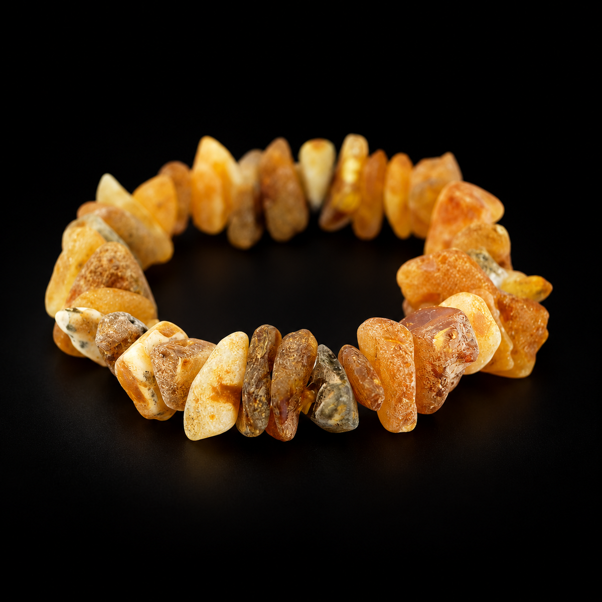 KIZIMA raw amber chip bracelet with honey, cream and olive stones in black studio light.