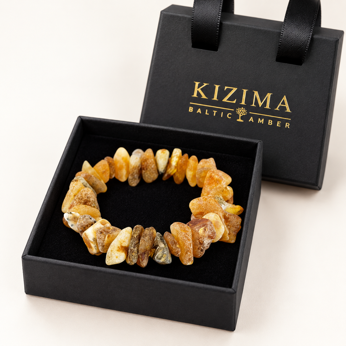 Raw multicolor amber chip bracelet on immaculate black velvet inside its KIZIMA gift box.