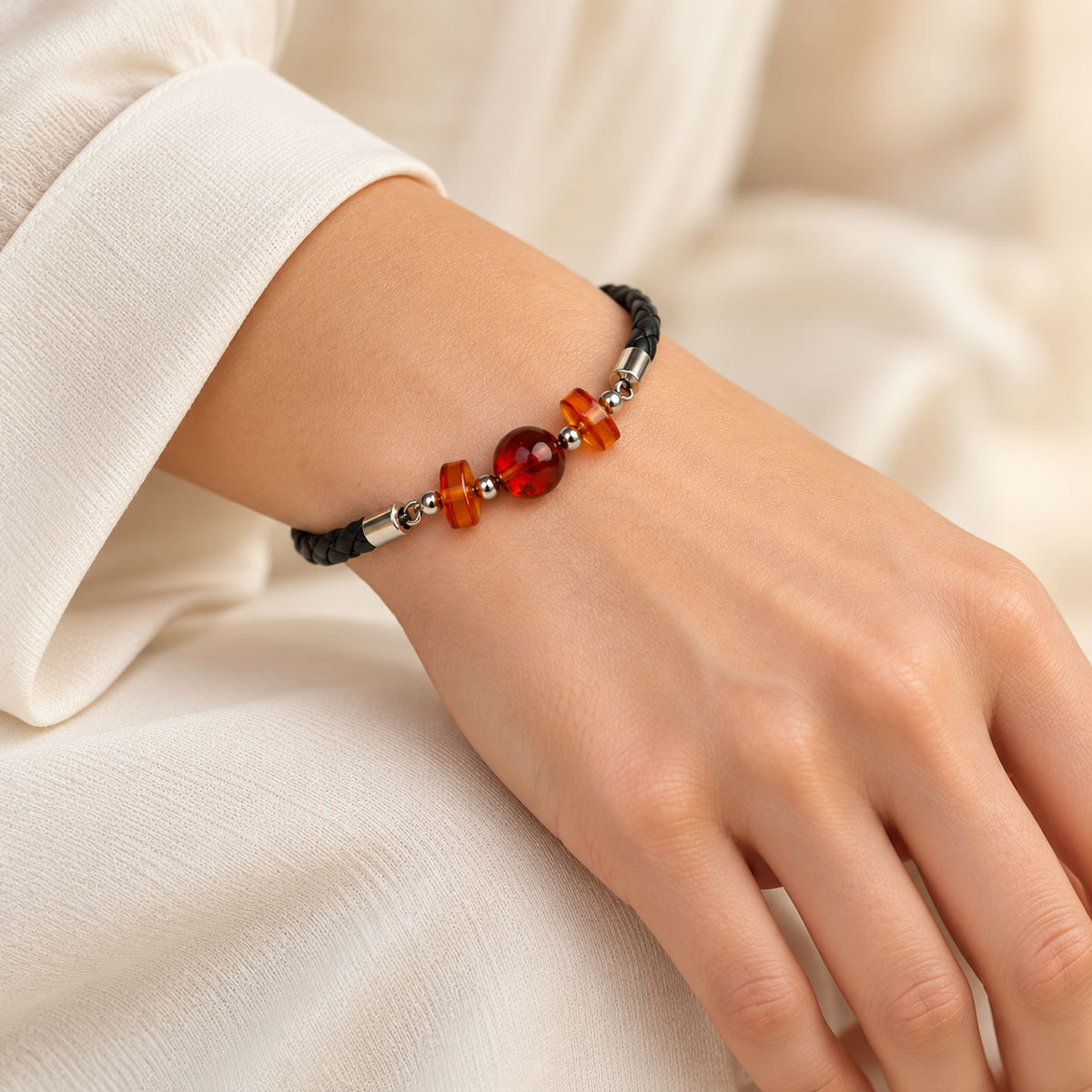 KIZIMA cherry amber three-bead black braided leather bracelet on a young adult woman's wrist.