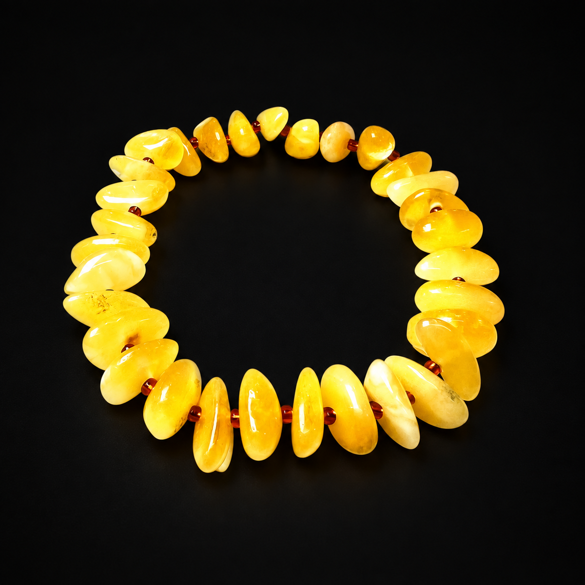 KIZIMA 3N0200q11.50 yellow amber chip bracelet with reddish-brown spacers on a black studio surface