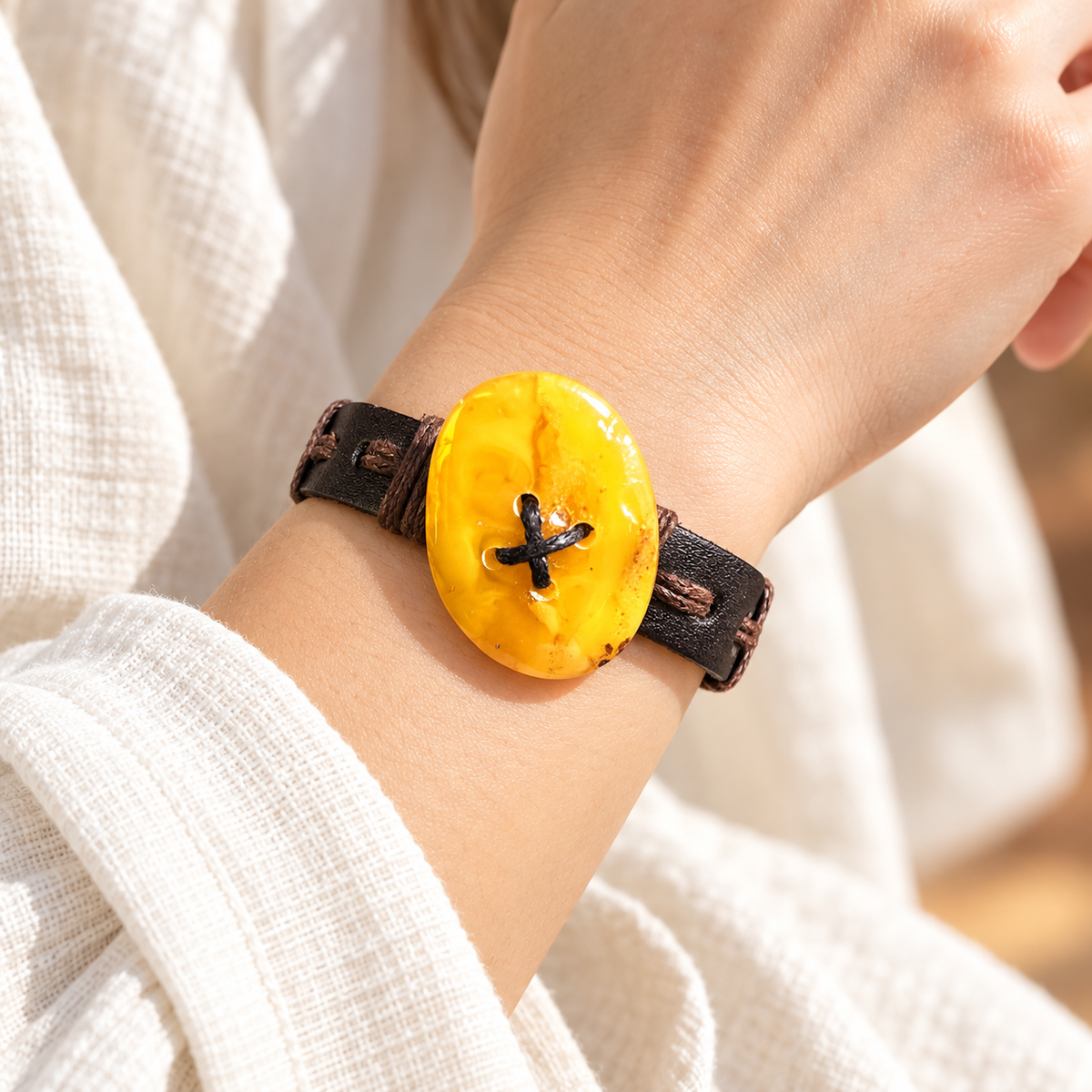 KIZIMA yellow oval amber and flat dark leather bracelet worn on a young adult woman's wrist