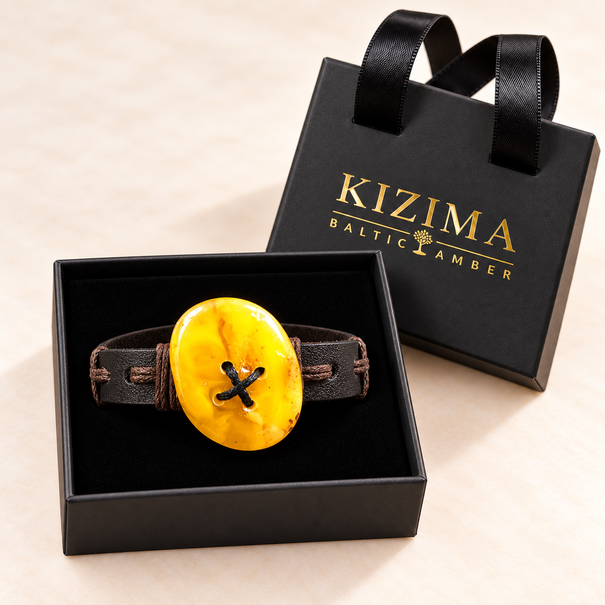 KIZIMA yellow oval amber and flat dark leather bracelet on black velvet inside its handled-lid gift box