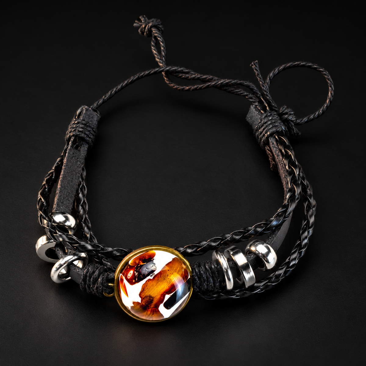 KIZIMA black braided leather bracelet with a round cognac amber medallion and silver-tone rings in black studio light.