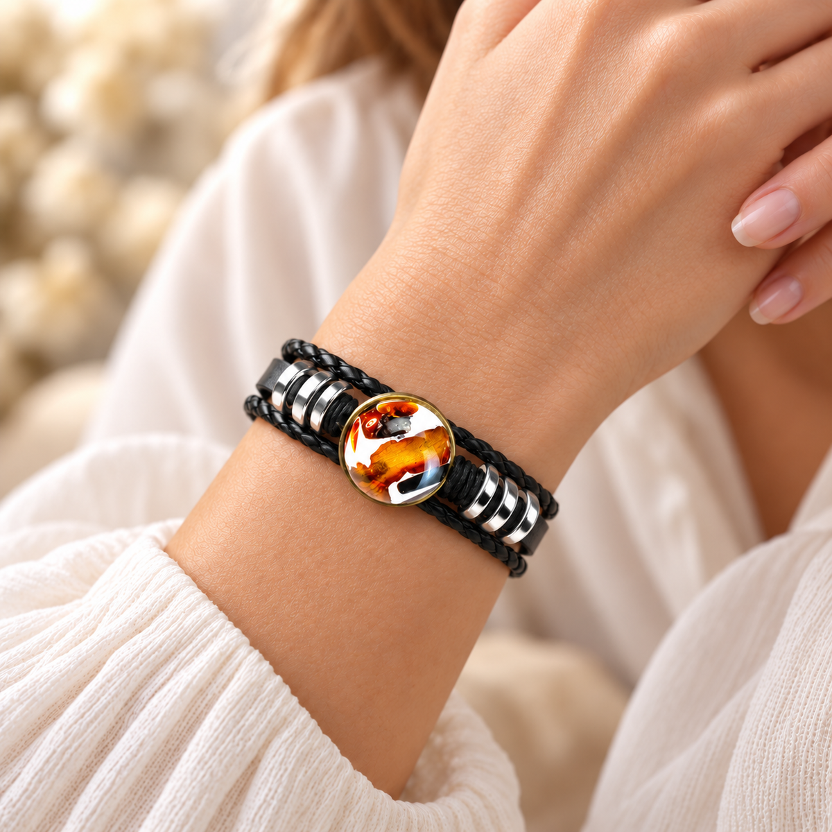 Amber medallion and layered black leather bracelet shown on a woman's wrist with its silver-tone ring accents.