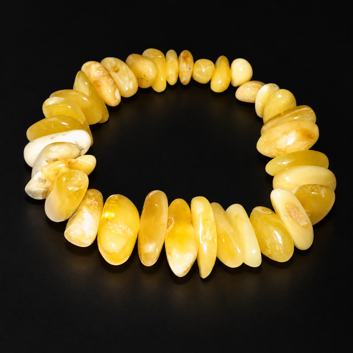 KIZIMA 3N0250q22.6 cream and yellow amber pebble bracelet on a black studio surface