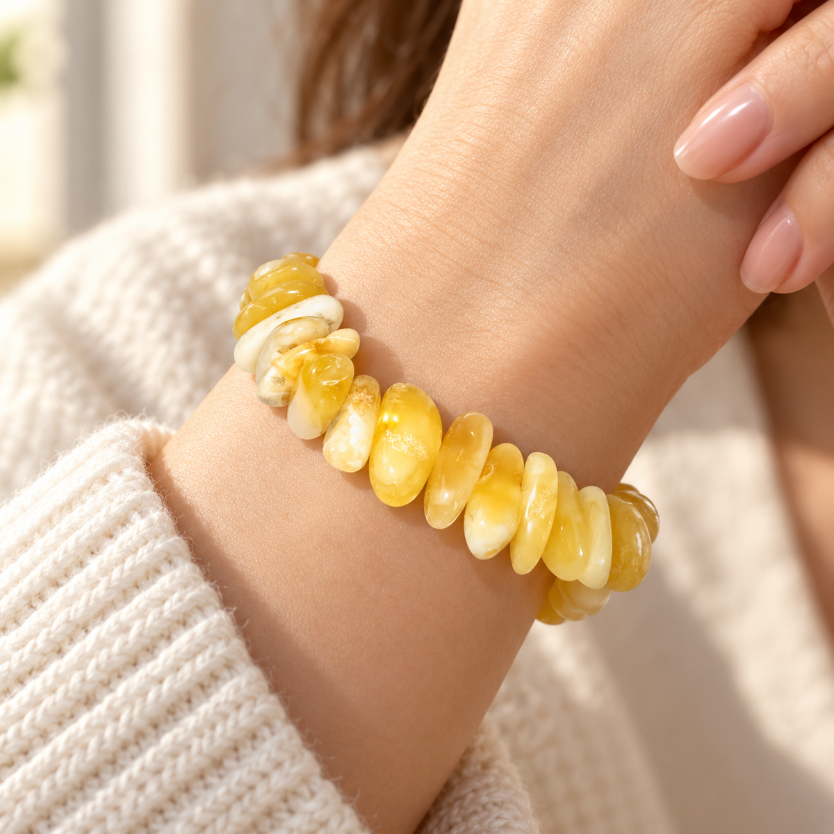 KIZIMA 3N0250q22.6 cream and yellow amber pebble bracelet worn on a woman's wrist