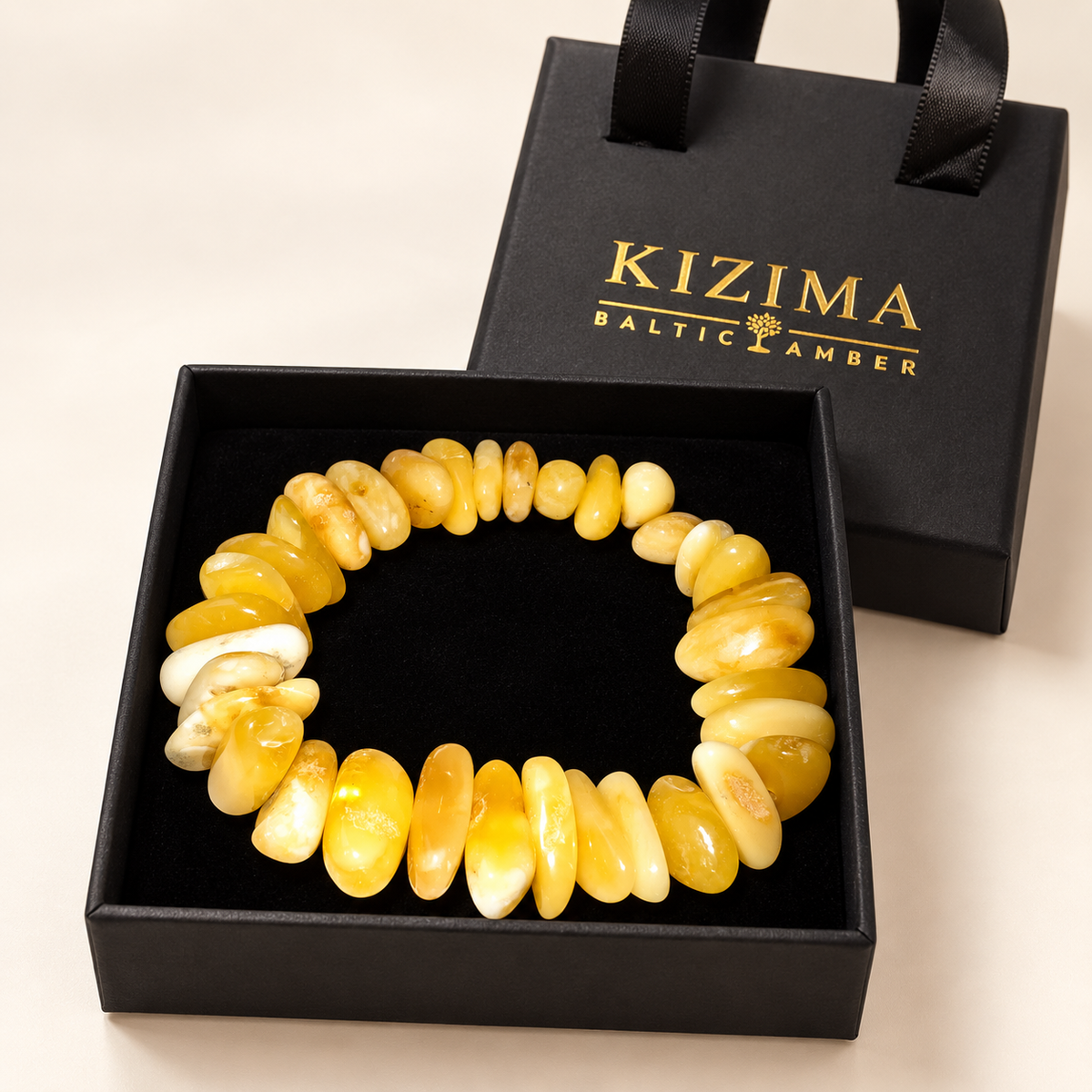 KIZIMA 3N0250q22.6 cream and yellow amber pebble bracelet on clean black velvet in its KIZIMA gift box