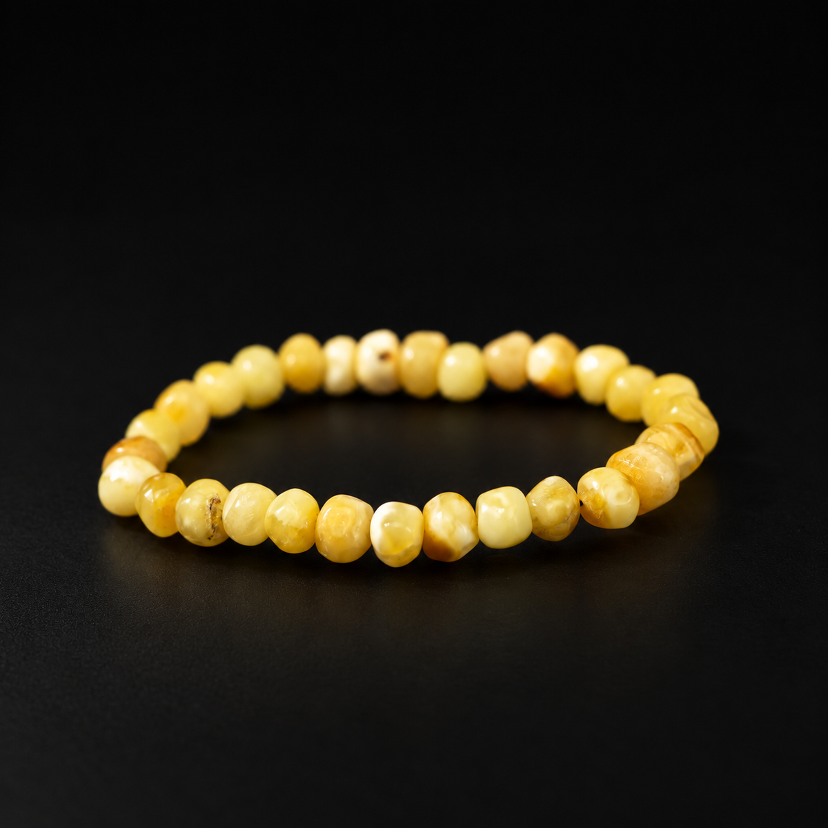 KIZIMA creamy yellow amber rounded nugget bracelet on a black studio background.