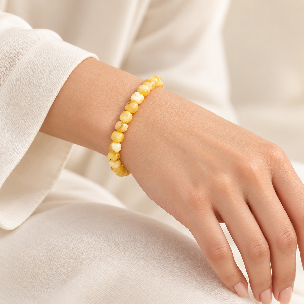 KIZIMA creamy yellow amber rounded nugget bracelet on a young adult woman's wrist.