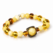 Amber bead bracelet with cream sphere in a dark square frame on pure white.