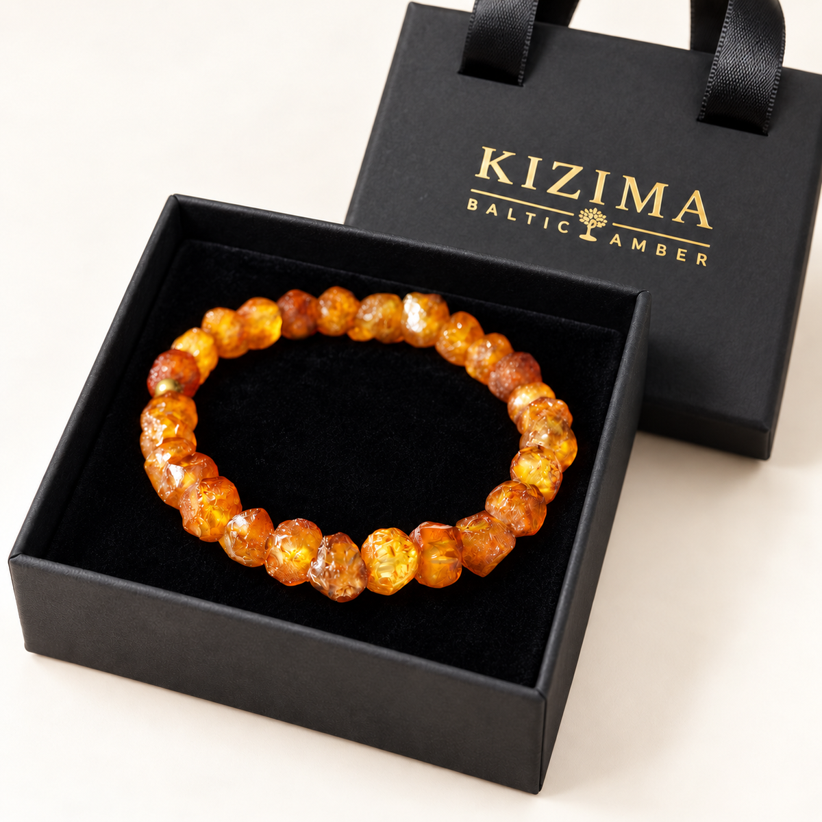 Raw honey and cognac amber bracelet on spotless black velvet in a KIZIMA gift box.