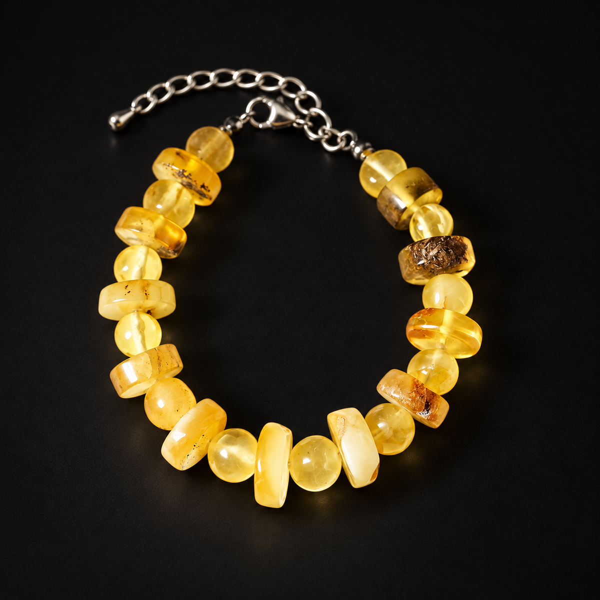 KIZIMA cream and yellow amber bead bracelet with silver-tone clasp and extender on black.