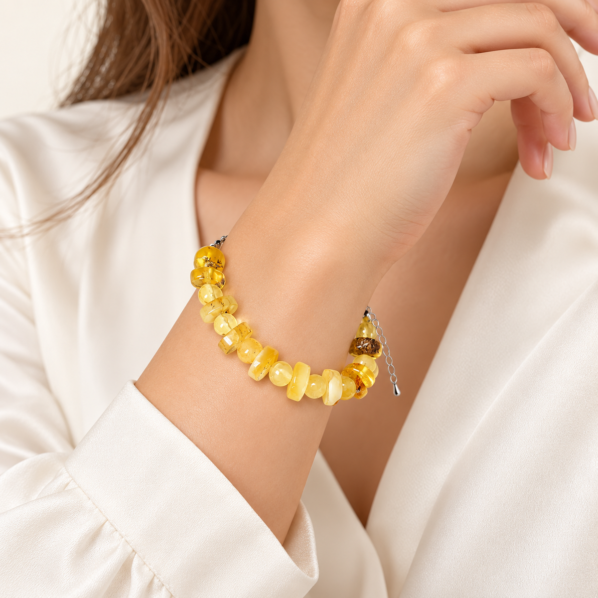 Alternating round and flattened amber beads on a young adult woman's wrist.