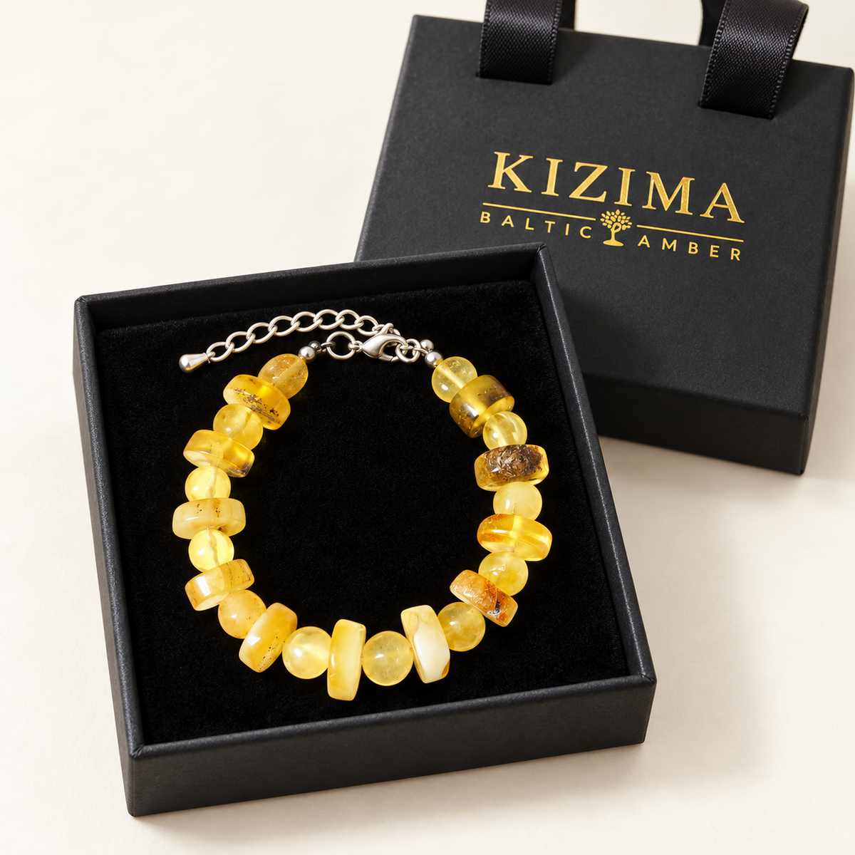 Cream and yellow amber bracelet displayed on pristine black velvet in a KIZIMA gift box.