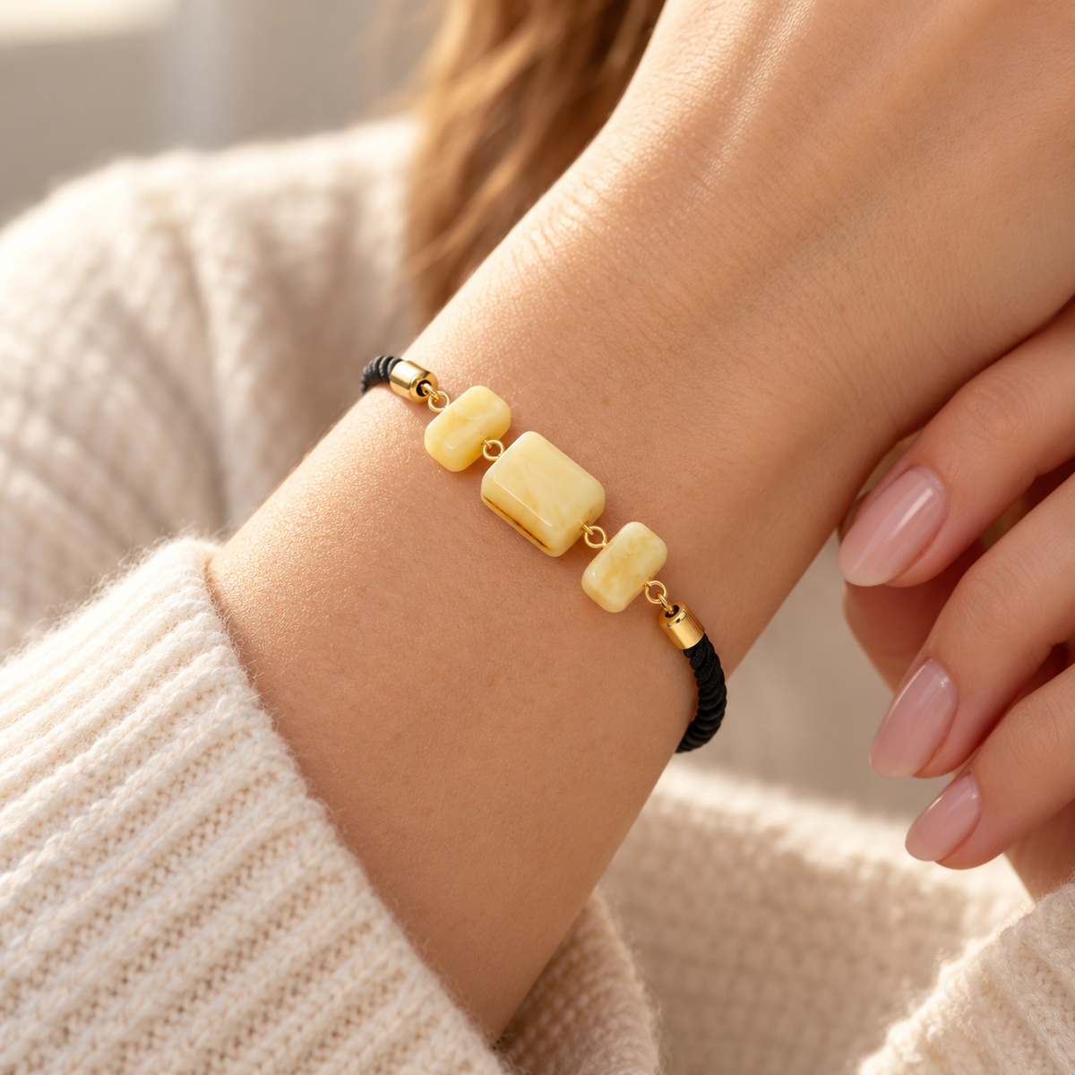 KIZIMA 3P0450q4.75 bracelet with three cream amber blocks and black cord worn on a woman's wrist