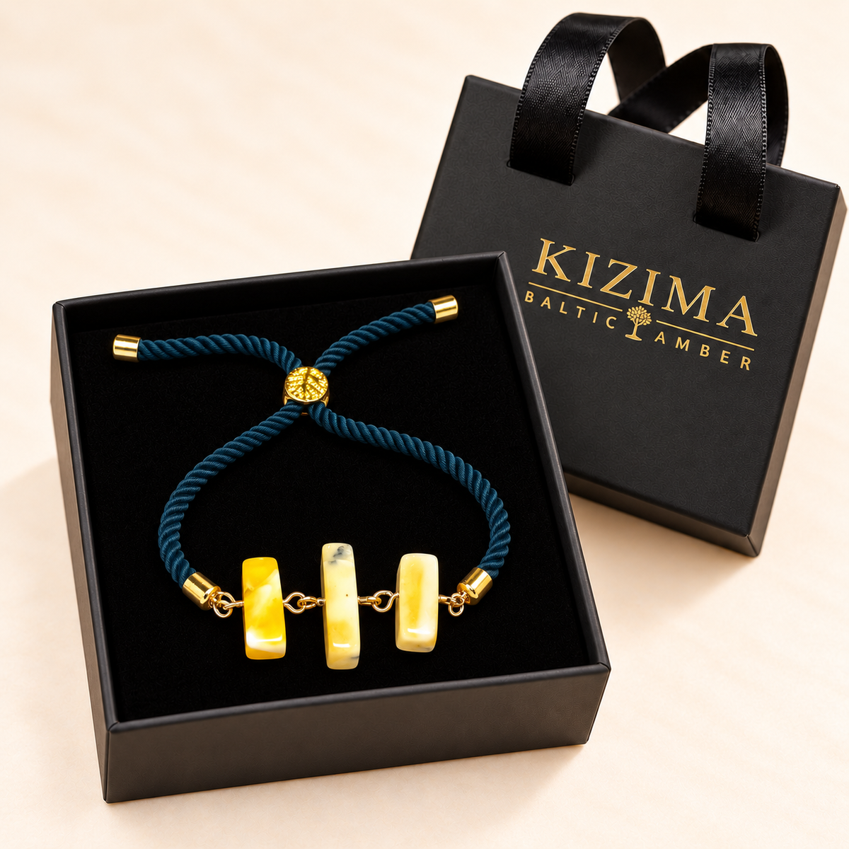 Teal rope bracelet with three creamy amber bars displayed on pristine black velvet in a KIZIMA gift box