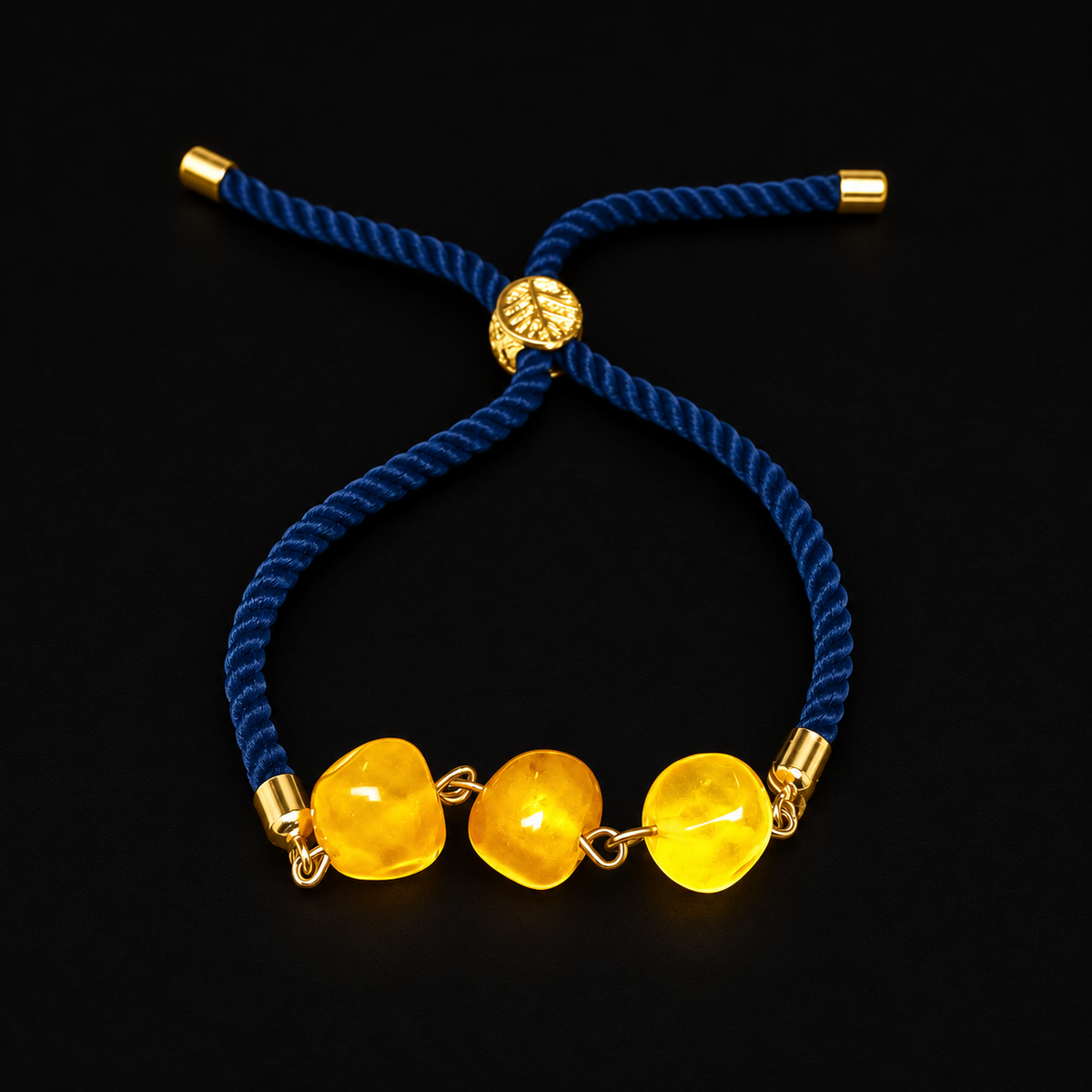 KIZIMA 3P0500q5.73 bracelet with three yellow amber beads and navy cord on a black studio surface